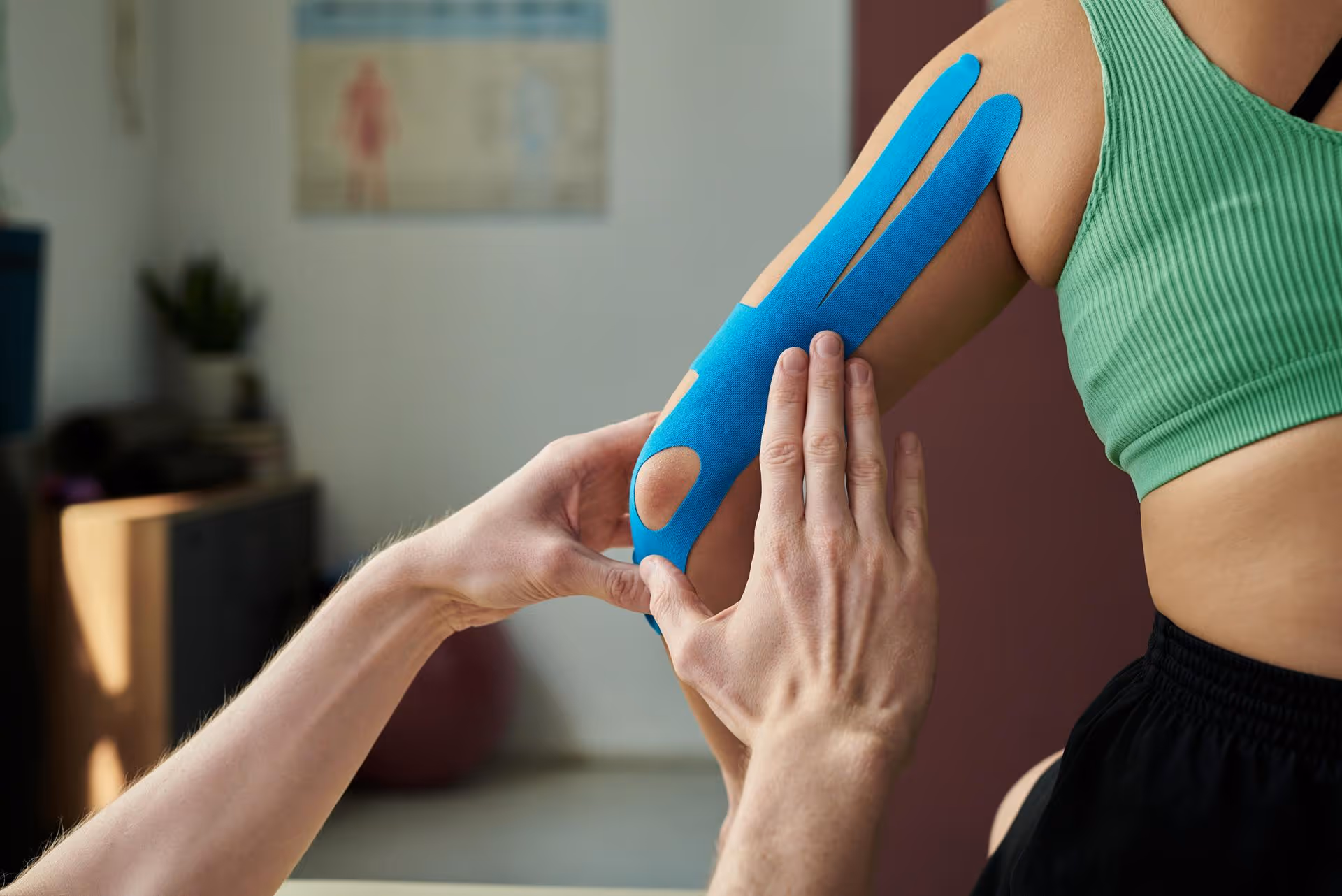 Physiotherapist applying kinesiology tape to a patient's arm.
