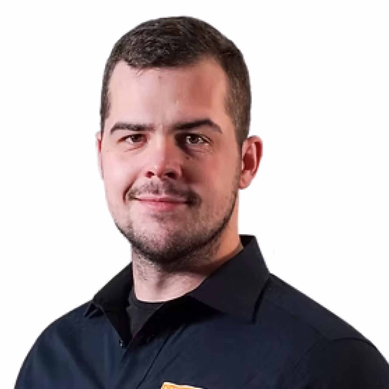 Man with short dark hair and light facial hair wearing a dark collared shirt, smiling slightly.