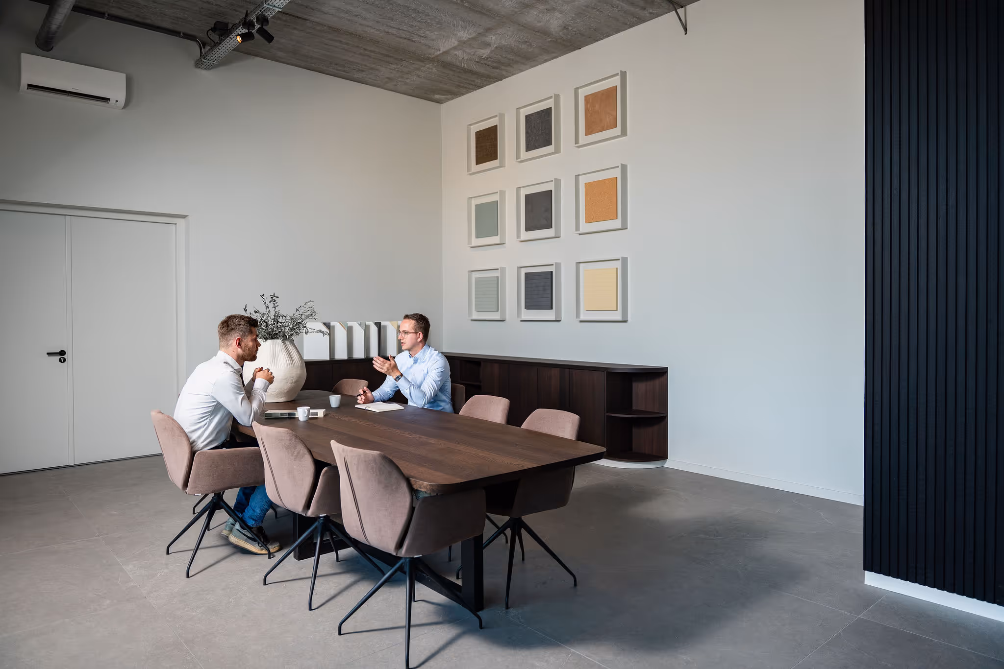 Two men seated at a modern conference table having a discussion in a minimalist office.