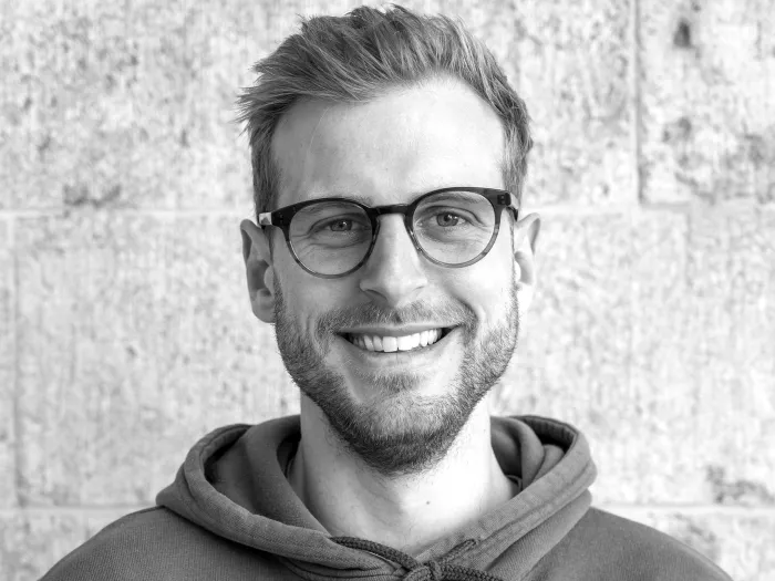 Black and white portrait of Jakob Brunnenkant, wearing glasses and smiling.
