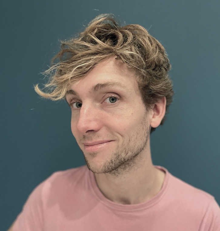 Portrait of Michael Lausberg, smiling, wearing a colorful patterned shirt in an outdoor setting.