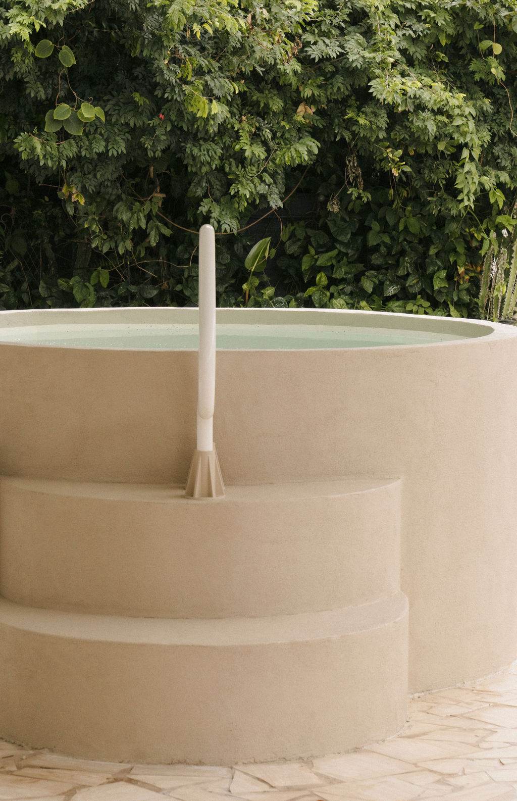 Cold plunge pool with concrete steps surrounded by valley greenery