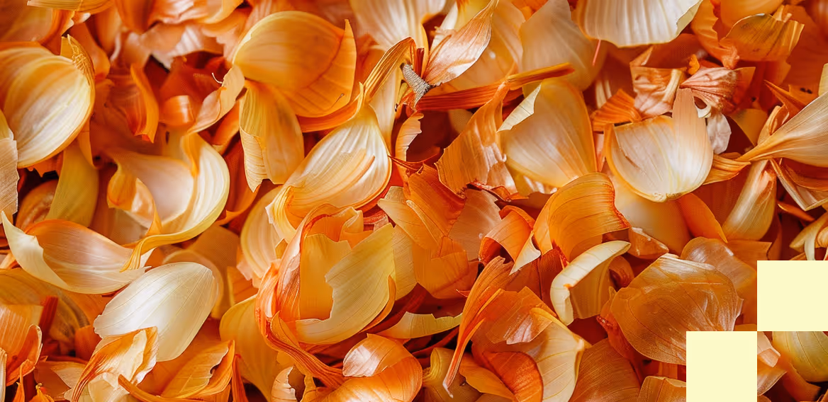 Close-up of a pile of orange and light yellow flower petals with delicate texture and soft lighting.