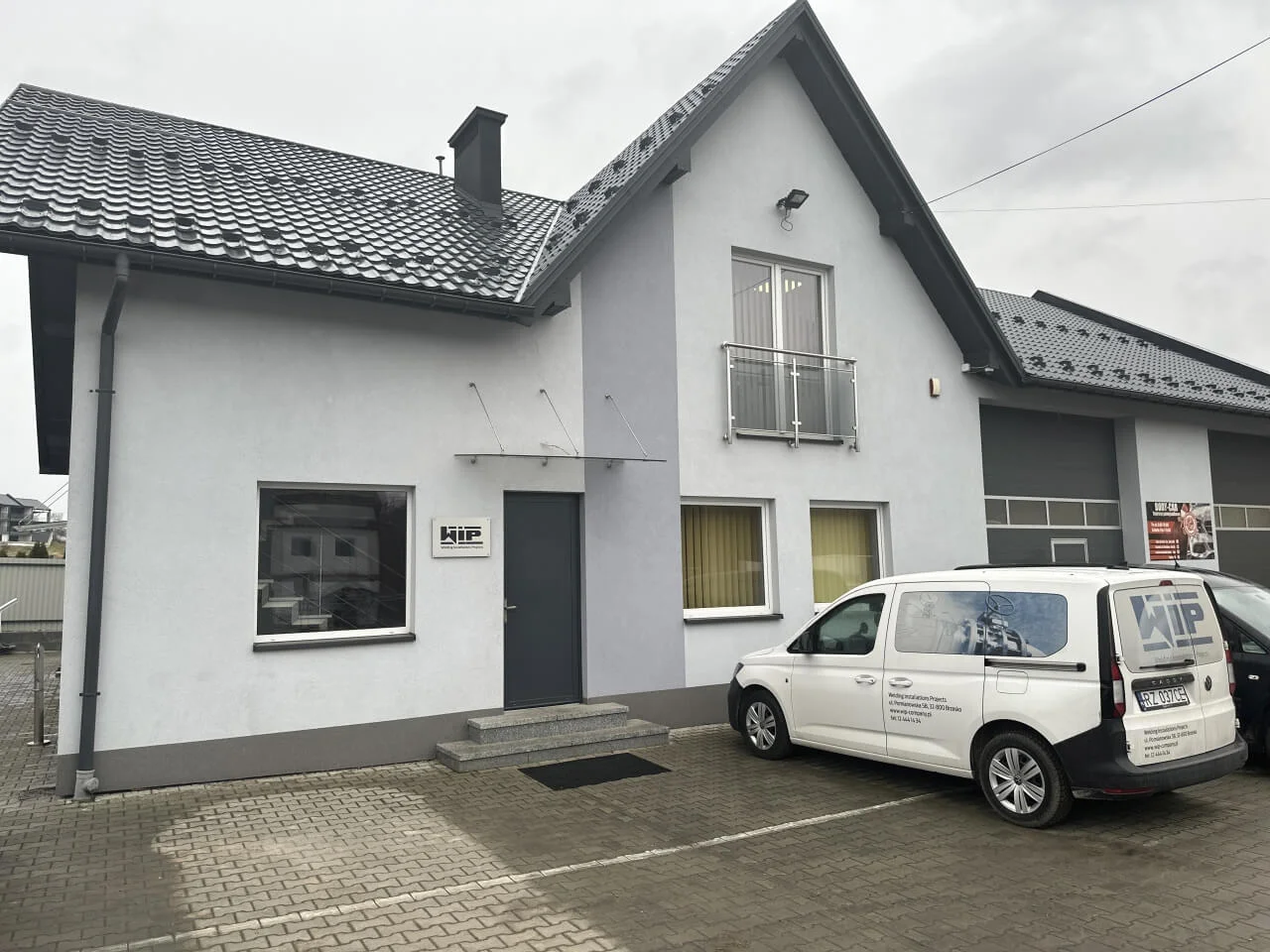 budynek biurowy z zaparkowanym przed nim samochodem 