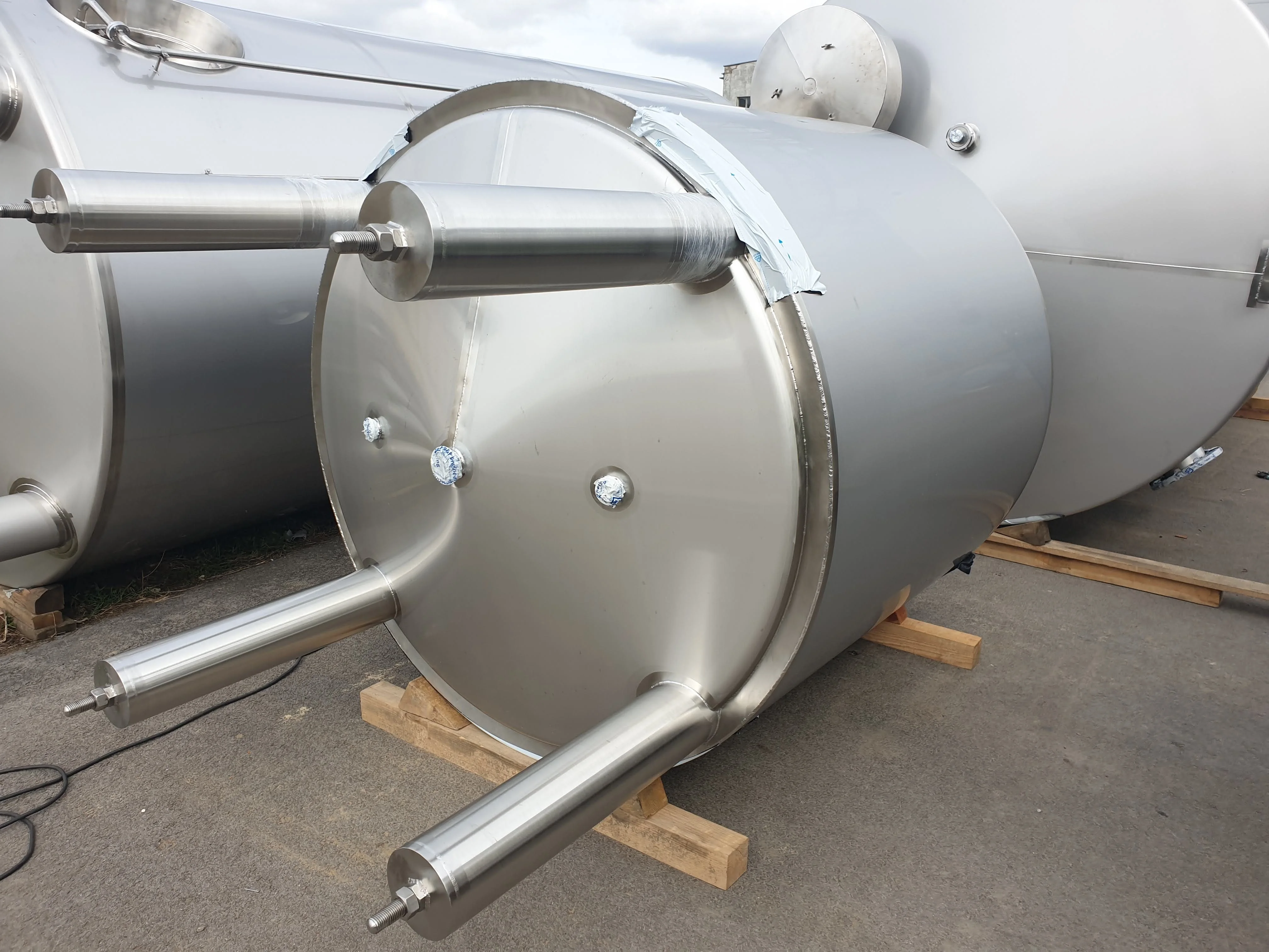 Grupa mężczyzn siedzi przy długim stole nakrytym białym obrusem i serwetkami, spożywając posiłek w eleganckiej sali z żyrandolami.