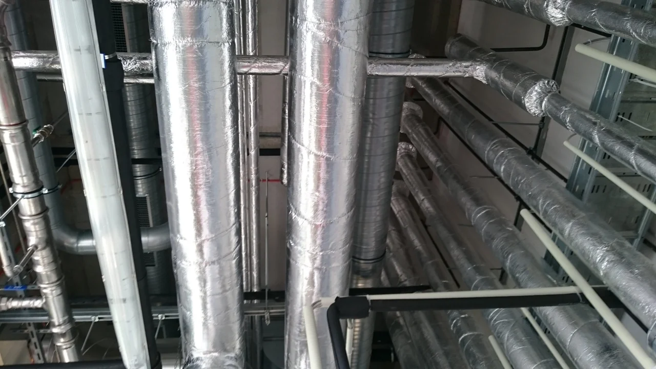 Izolowane metalowe rury i przewody zainstalowane na suficie technicznym.