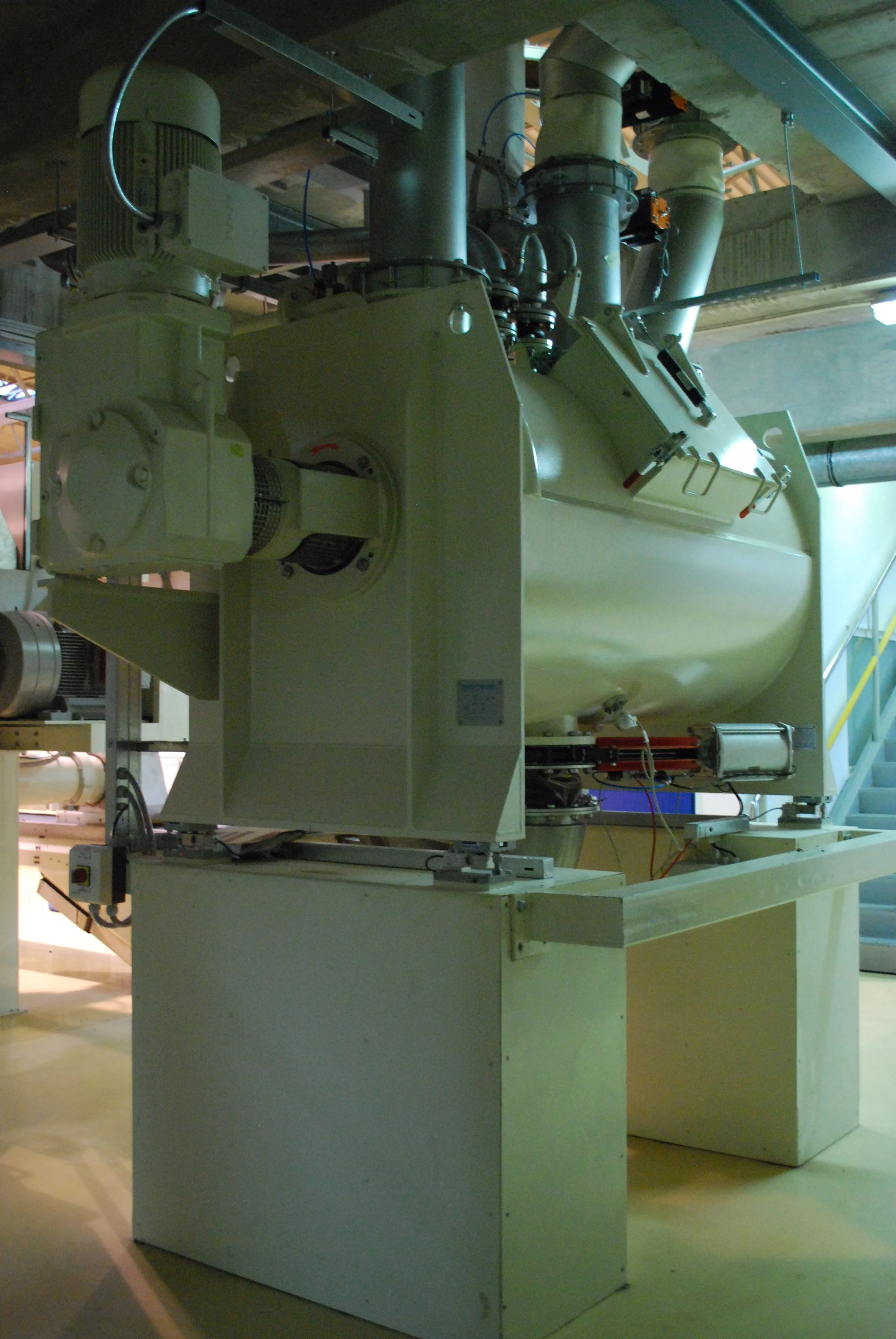 Duża przemysłowa maszyna mieszająca z silnikiem elektrycznym w pomieszczeniu technicznym.