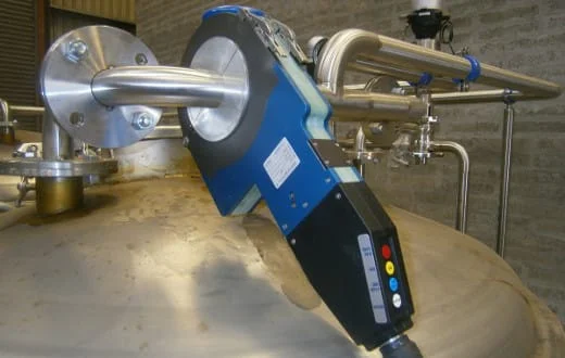 Mężczyźni siedzący przy długim stole nakrytym białym obrusem i udekorowanym świecznikami, w sali bankietowej z drewnianą podłogą.