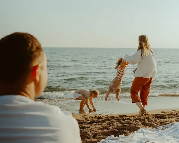 Instant de partage en famille sur une plage sous le soleil, illustrant les moments de vie authentiques et l'ancrage local proposés par Anchor à Cannes.