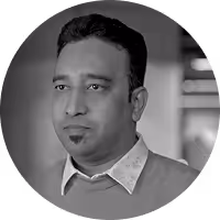 Portrait of a man with short hair wearing a collared shirt and sweater, looking slightly to the left.