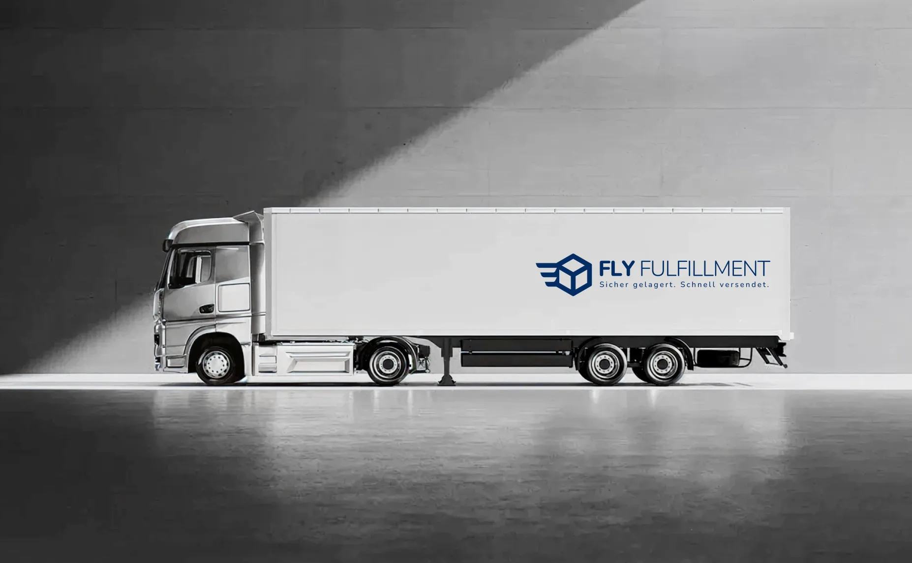 Silver semi-truck parked indoors with white trailer displaying Fly Fulfillment logo and slogan in German.