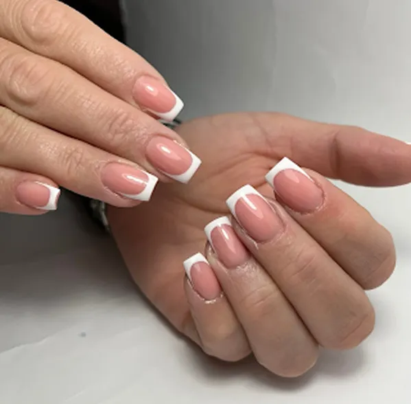 Close-up of hands with neatly manicured nails featuring classic French tip design