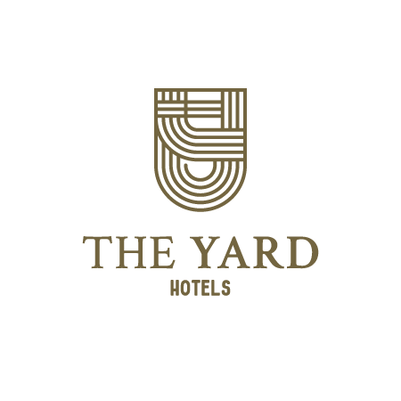 Logo for The Yard Hotels featuring a geometric shield icon above the text.