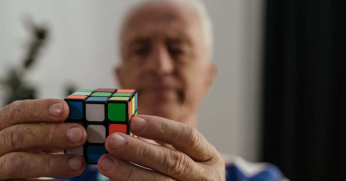 Sessão de estimulação cognitiva em grupo com pessoas idosas e terapeuta a orientar atividade estruturada sobre uma mesa