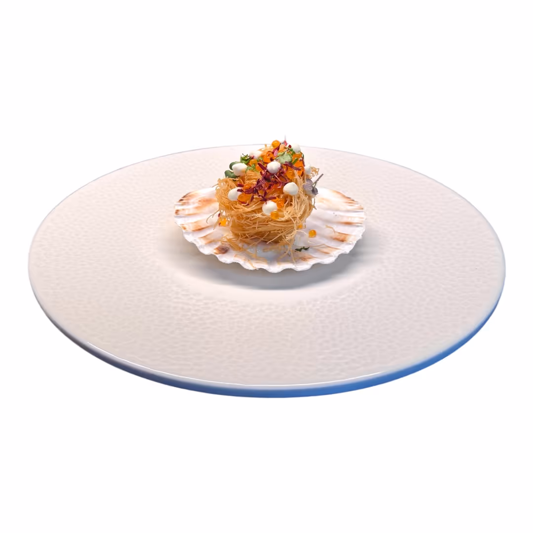 Feines Gourmet-Gericht mit knusprigem Nest, verziert mit kleinen weißen und orangen Kugeln auf einer Jakobsmuschel, serviert auf einem weißen Teller.