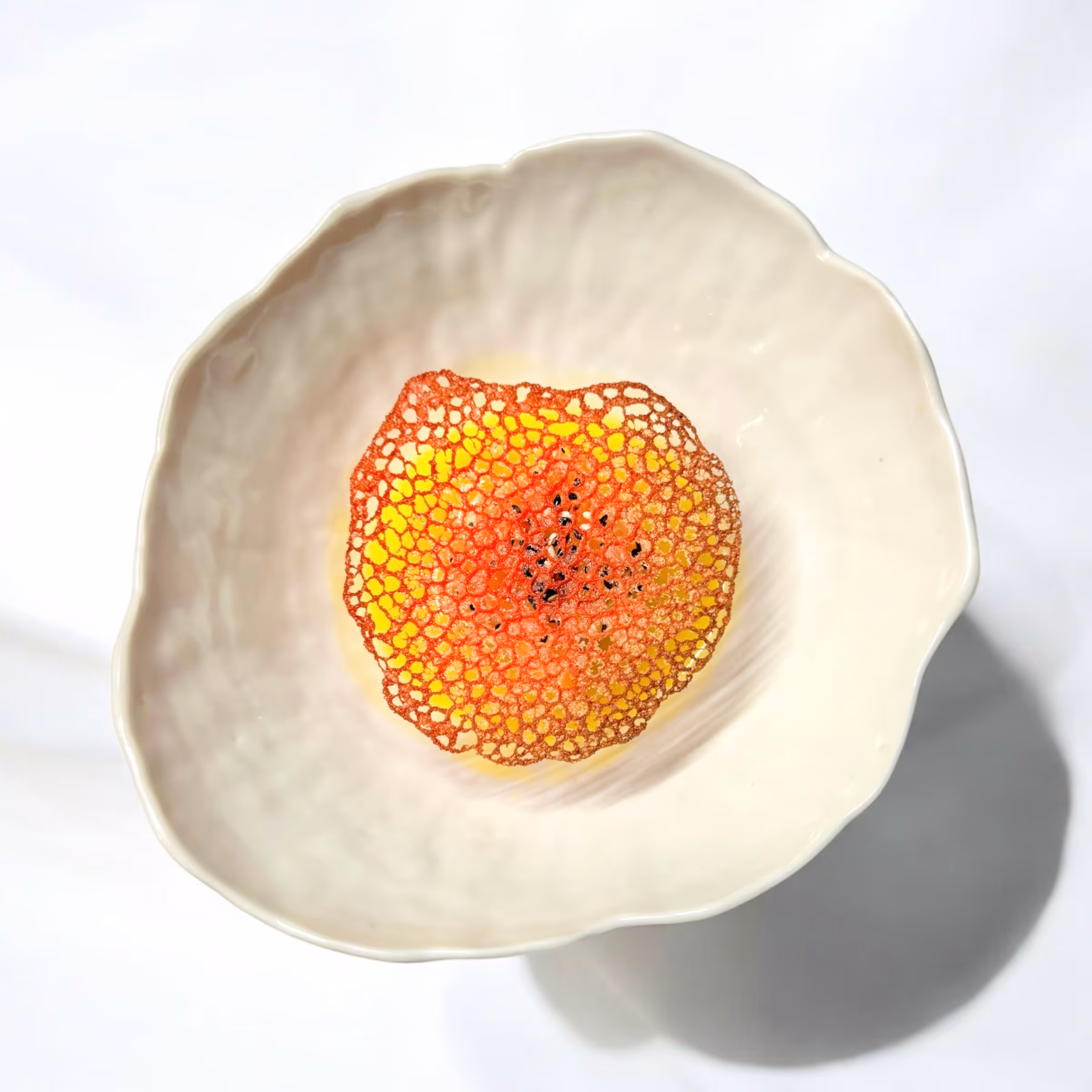 Weiße Schale mit einer filigranen, roten, netzartigen Dekoration in der Mitte.