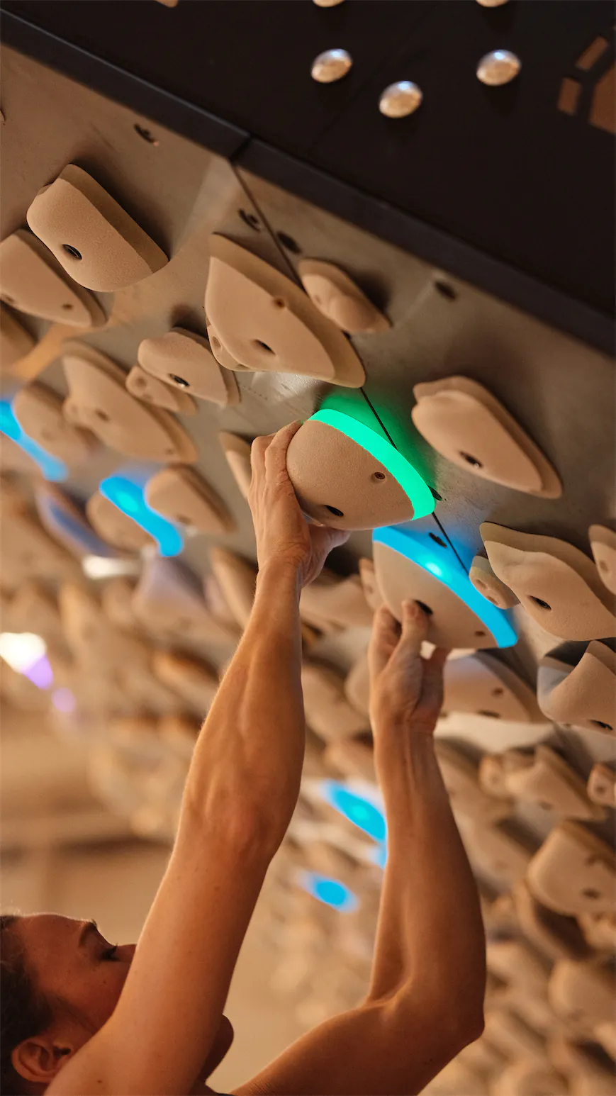 Gros plan sur des mains et prises lumineuses de board d'entraînement.