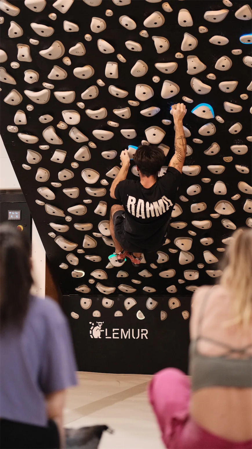 Grimpeur sur la board d'entraînement Lemur avec spectateurs.