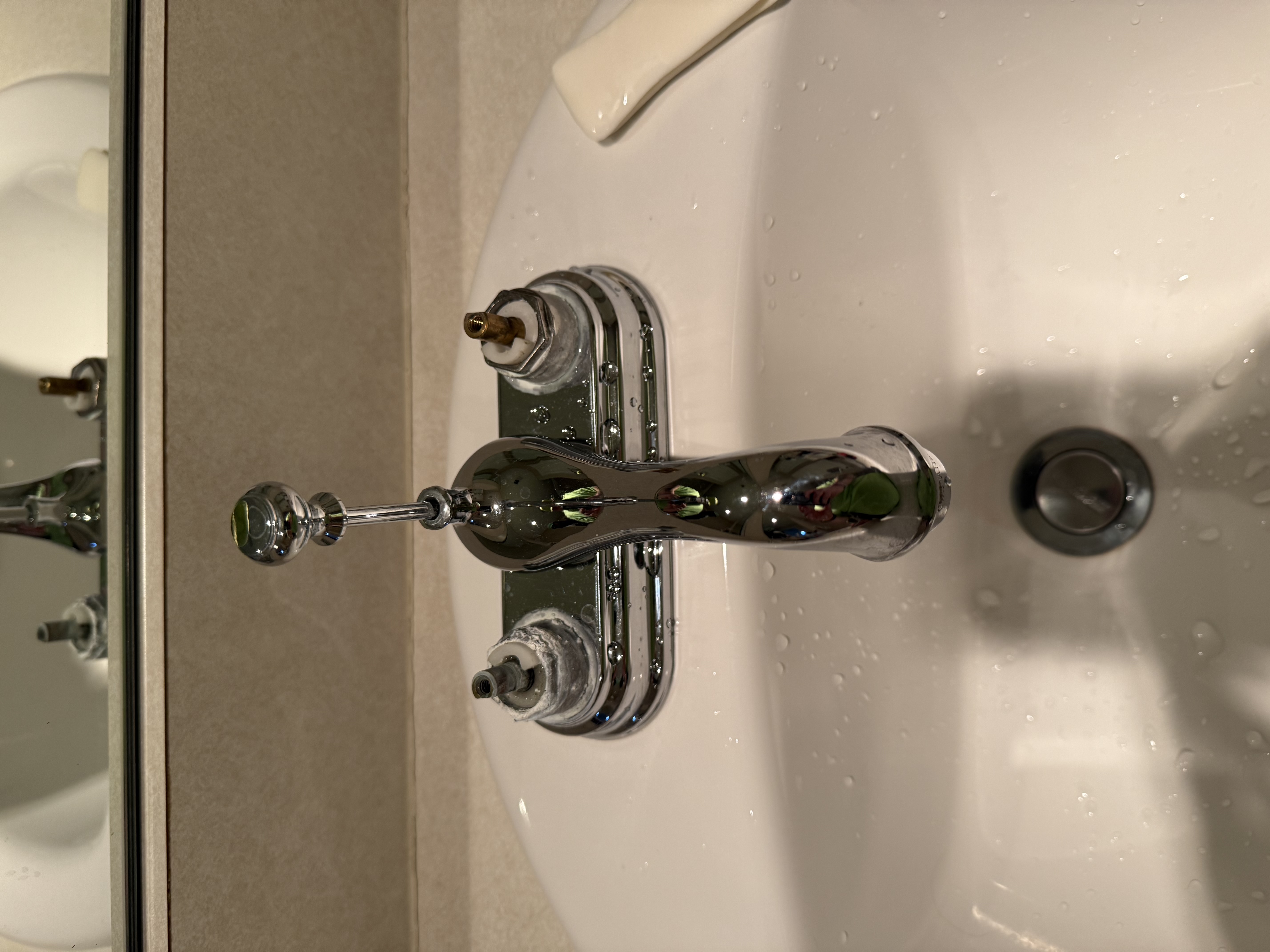 Bathroom sink with a chrome faucet missing its hot and cold handles.