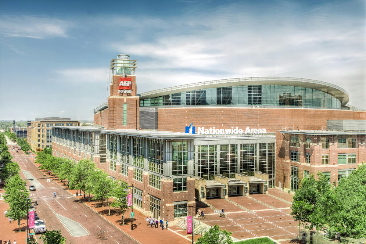 Exterior view of Nationwide Arena in Columbus with brick facade, large glass windows, and surrounding tree-lined streets.