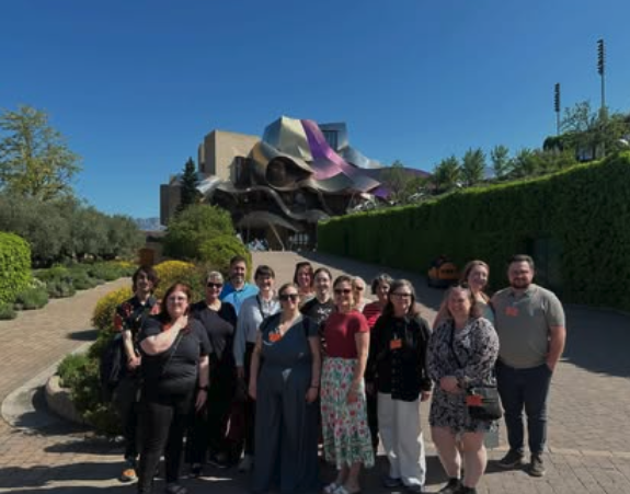 Group posing outside a modern winery building on a sunny day