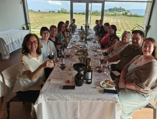 Group enjoying a wine tasting at a vineyard with panoramic hill views