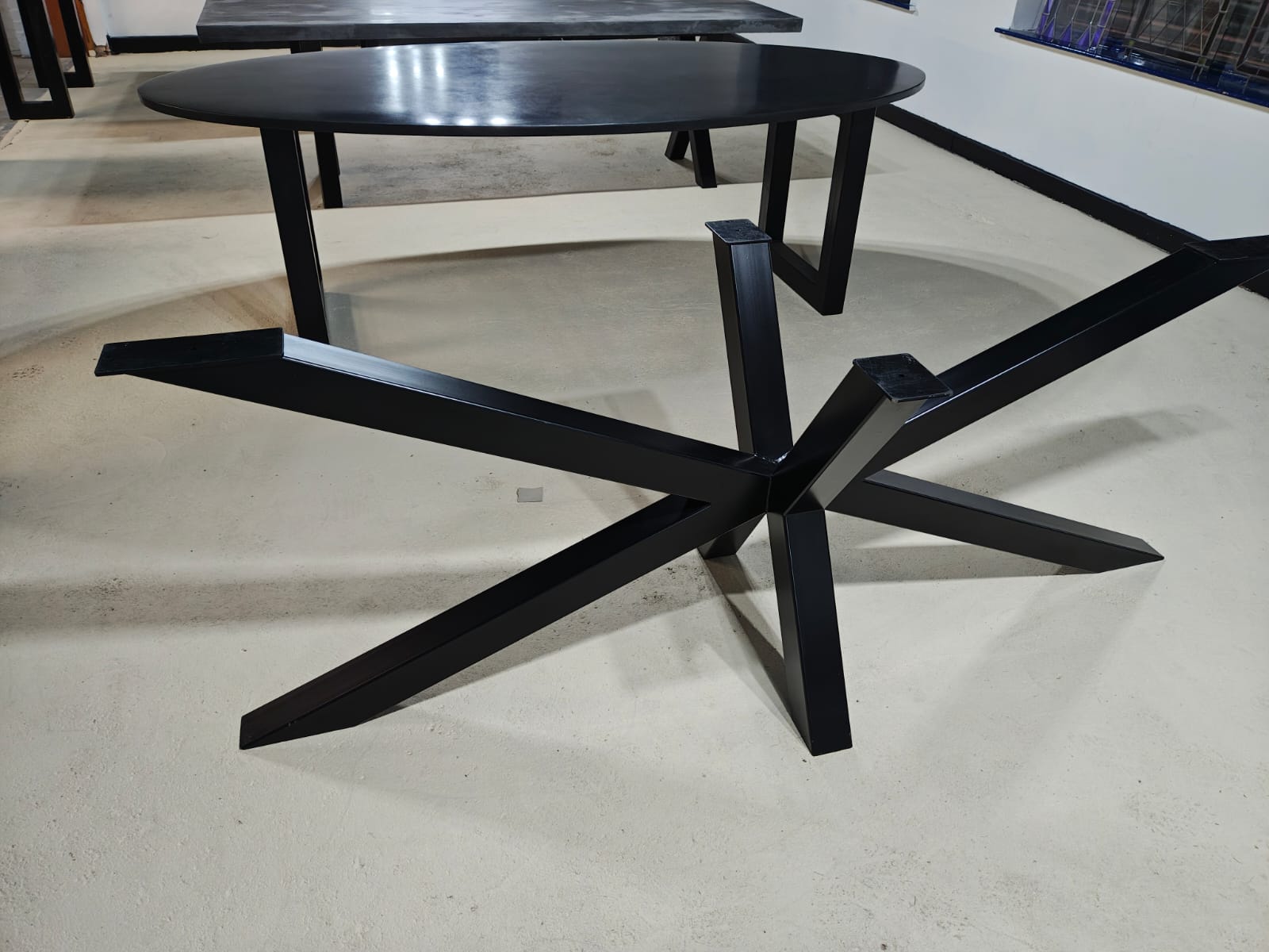 Black metal star-shaped table base designed to support an oval tabletop.