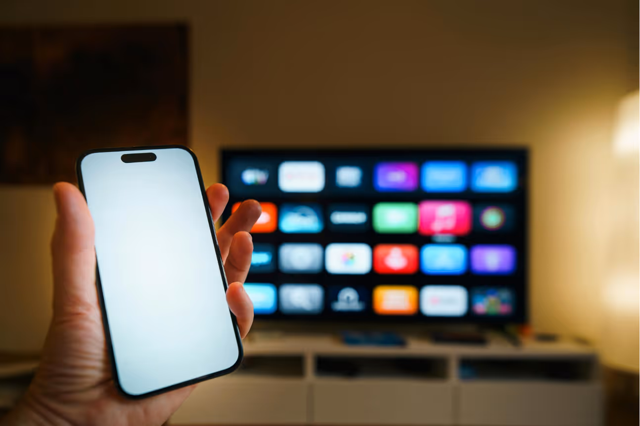 Smartphone vor Fernseher mit Streaming-Oberfläche