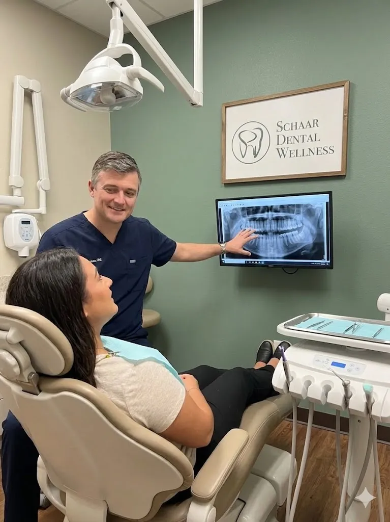 Dentist explaining a dental X-ray to a patient seated in a dental chair at Schaar Dental Wellness.
