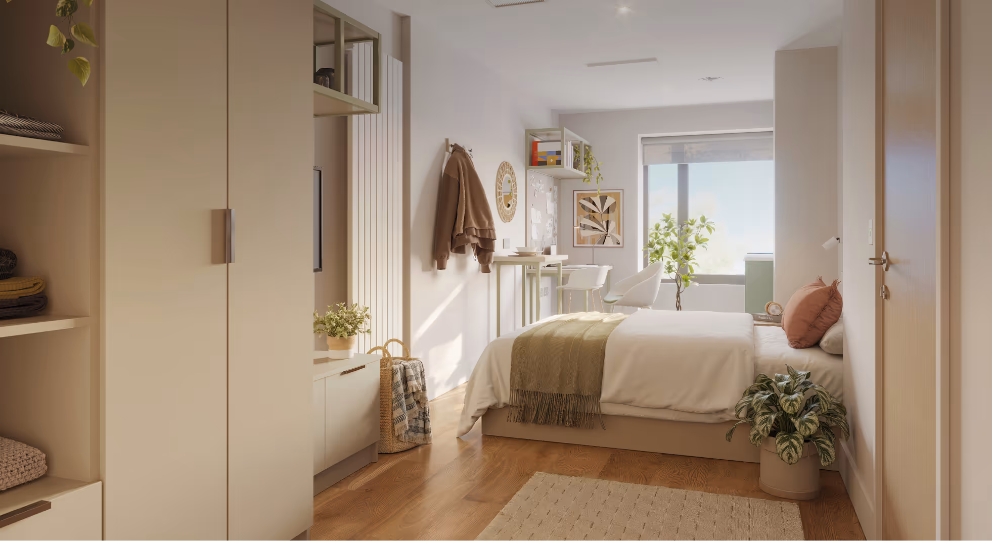 Bright bedroom with wooden floor, beige walls, a bed with green throw and pink pillows, plants, and a desk by a large window.