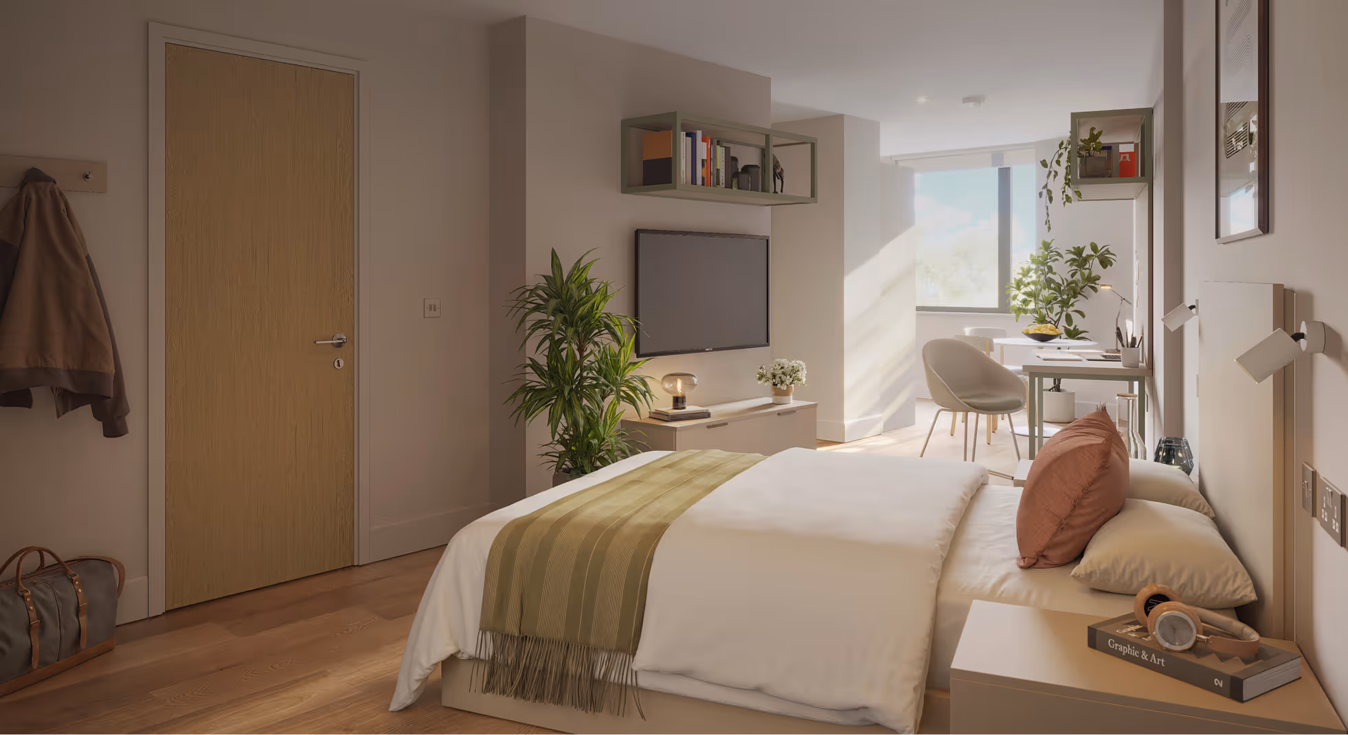 Modern bedroom with a neatly made bed with white bedding and a brown pillow, a green throw, a wall-mounted TV, indoor plants, a desk with a chair by a large window, and wooden flooring.