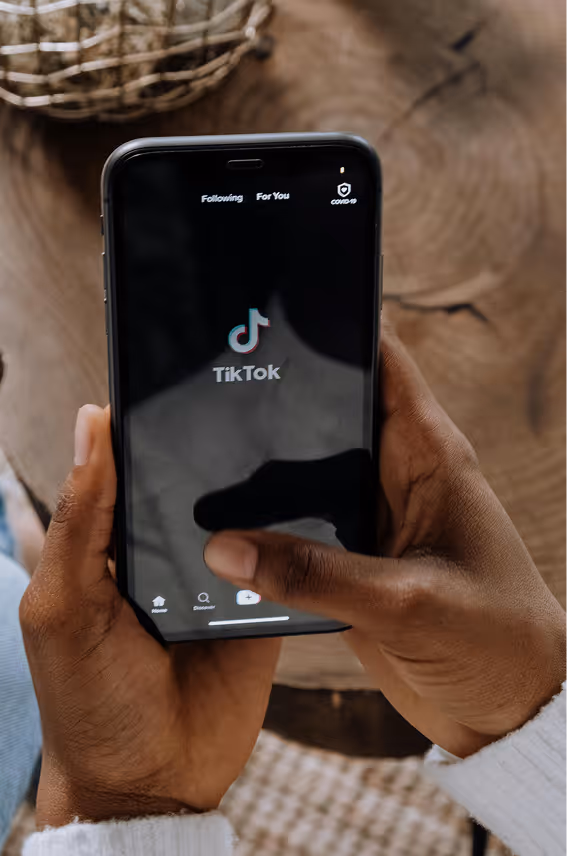 Person holding a smartphone displaying the TikTok app launch screen.