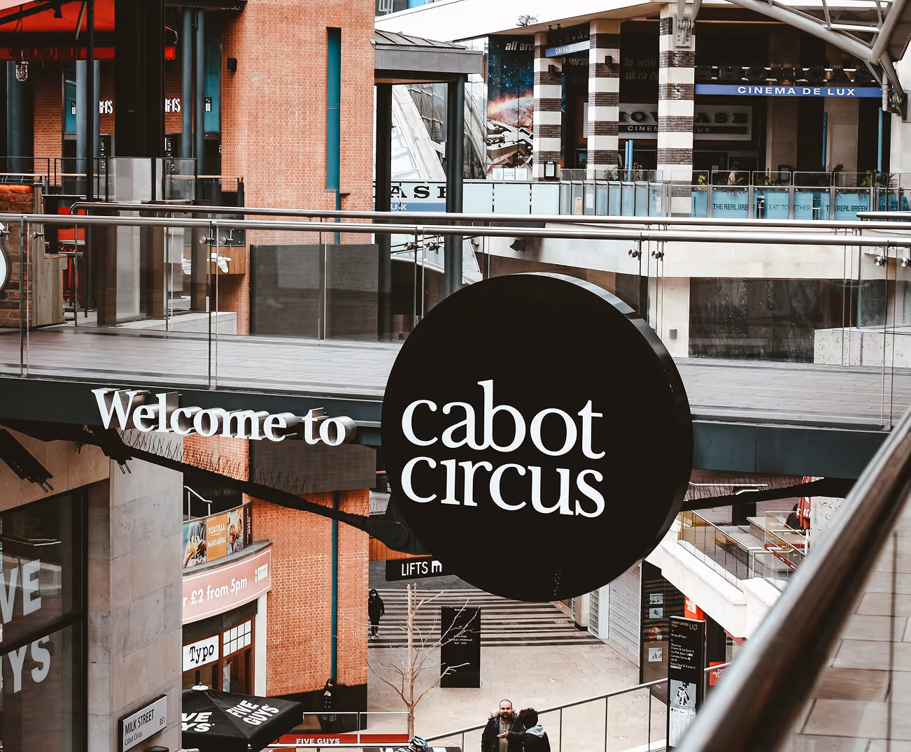 Black circular sign with white text reading 'cabot circus' and nearby text 'Welcome to' in a modern shopping center.