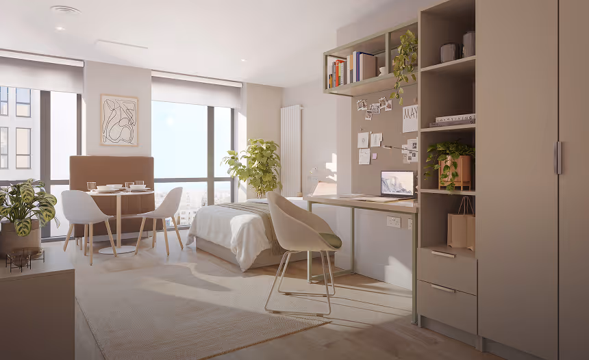 Bright, modern studio apartment with a bed, round dining table with chairs, desk with chair and computer, shelves with plants and books, large windows, and neutral tones.