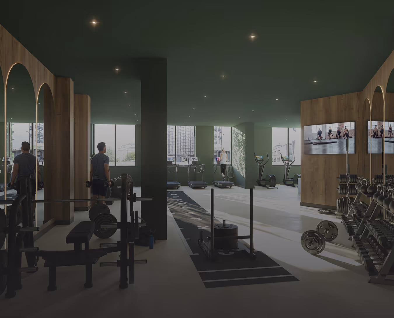 Modern gym with weight training area on the left, treadmills in the background, and dumbbell racks on the right with two people exercising.