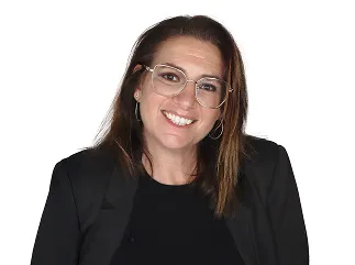 Femme souriante portant des lunettes et une veste noire sur fond blanc.