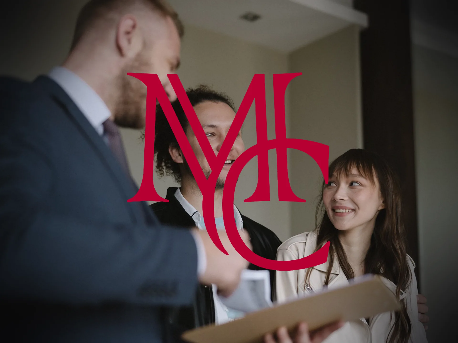 A real estate agent hands over a moving box to a smiling couple during a Northwest Arkansas home purchase — MCG