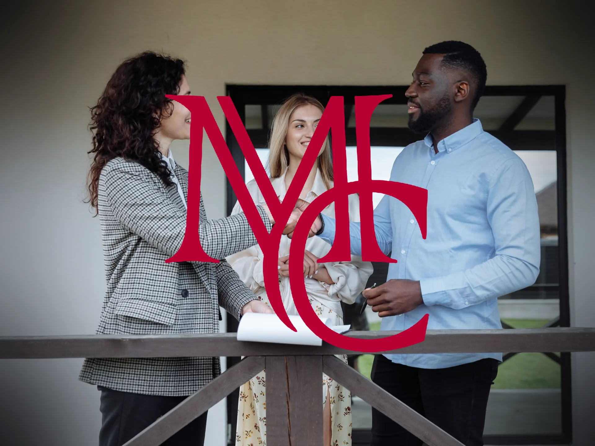 A real estate agent shaking hands with a couple on the porch of a home while reviewing paperwork — MCG