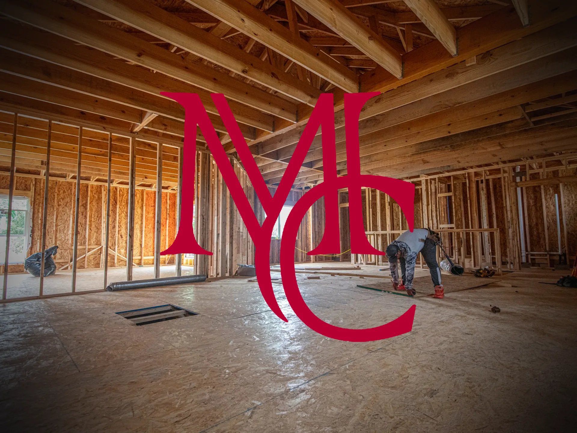 A construction worker installing subfloor inside a wood-framed house under construction — MCG