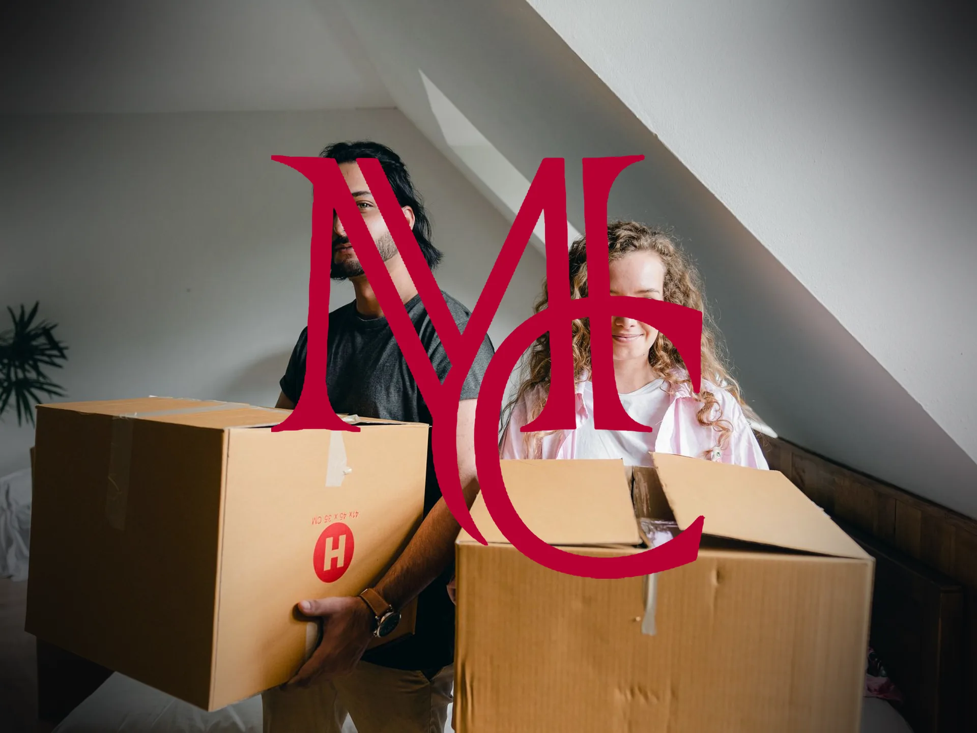 A couple carries cardboard moving boxes into the empty upstairs room of their new home — MCG