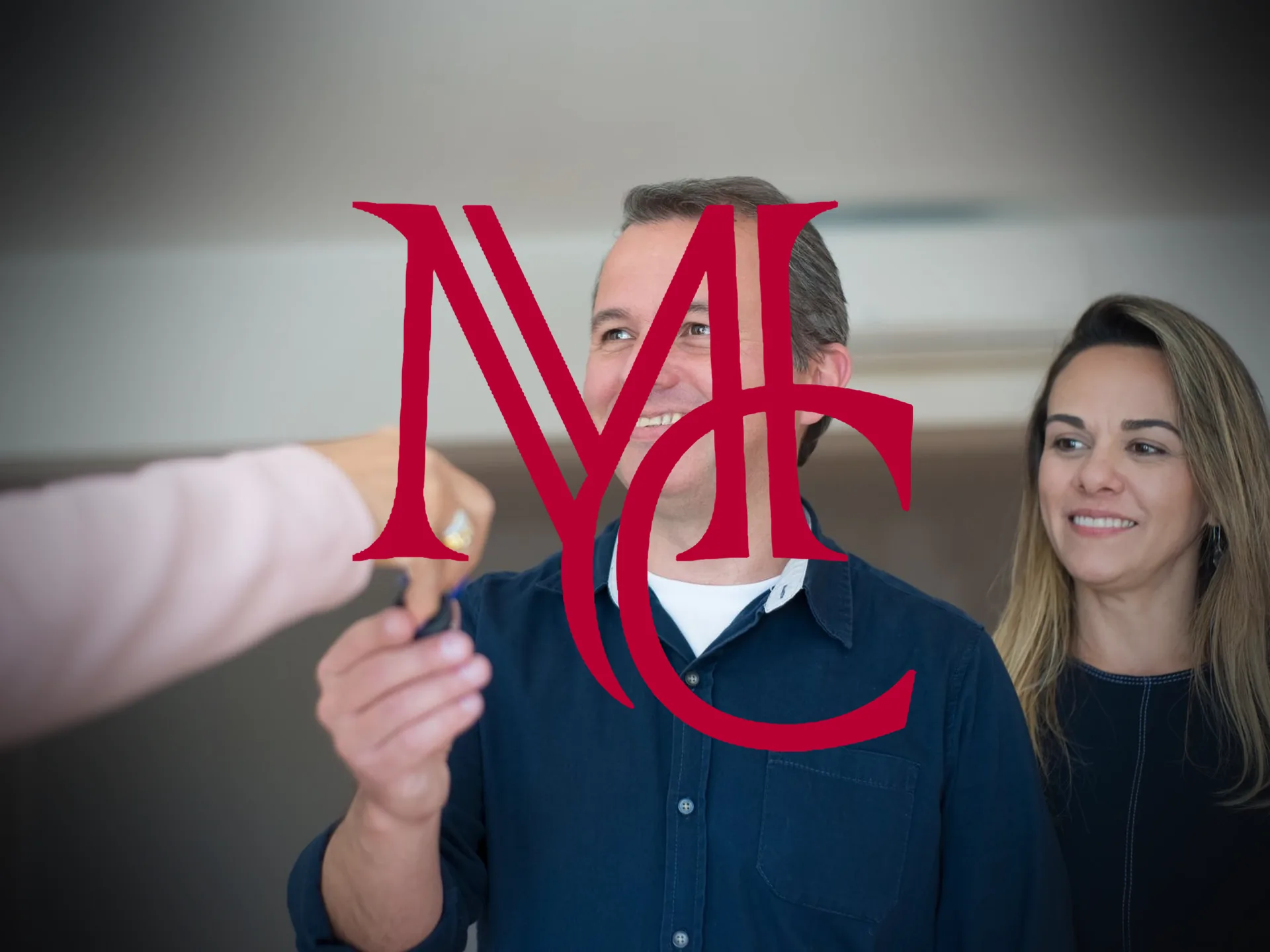 A real estate agent hands house keys to a smiling couple inside a bright, freshly finished home — MCG