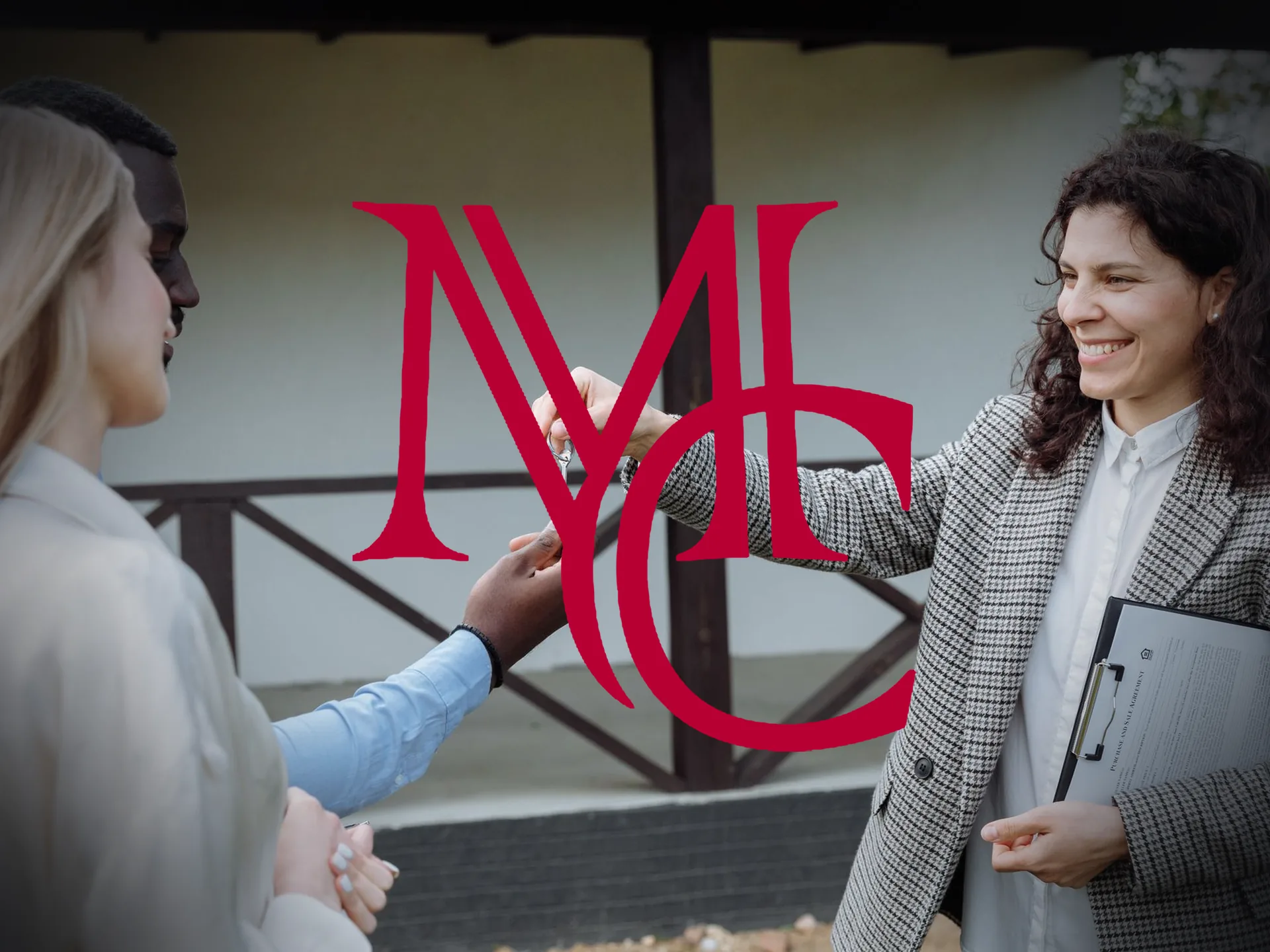 A real estate agent hands house keys to a smiling couple outside a home — MCG