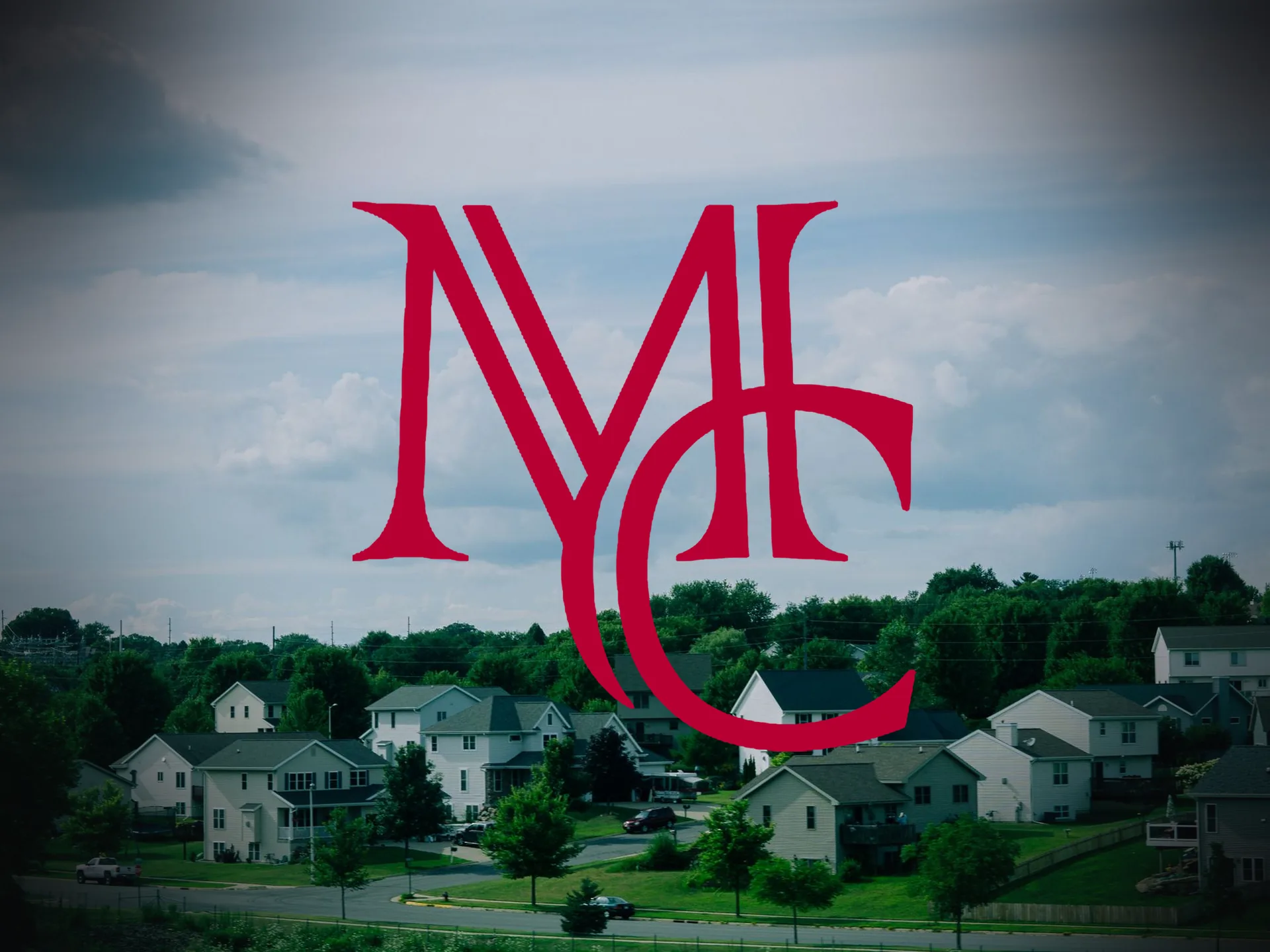A suburban neighborhood of modest two-story homes under a cloudy sky — MCG