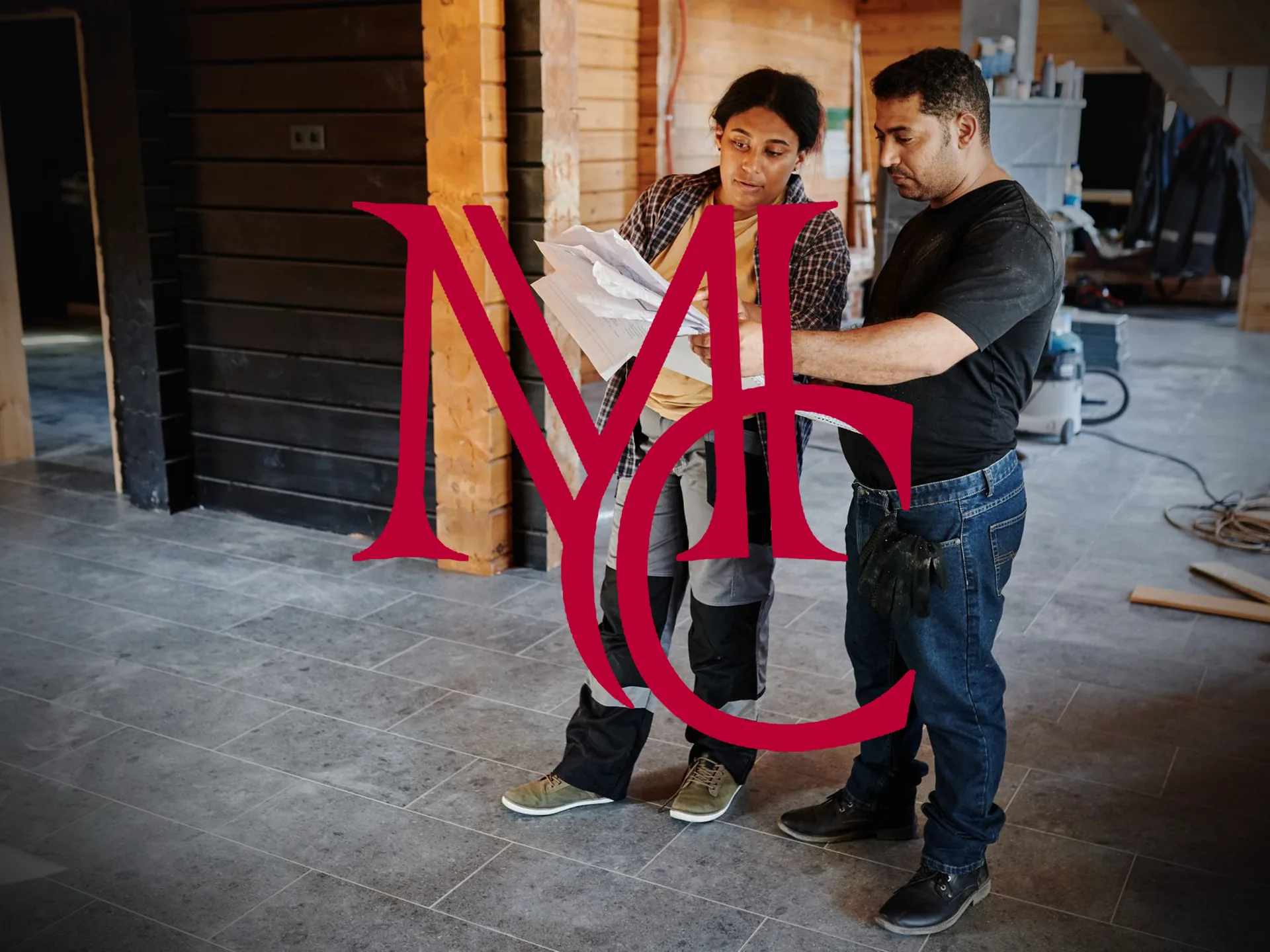 Two construction workers reviewing building plans inside a house under construction — MCG