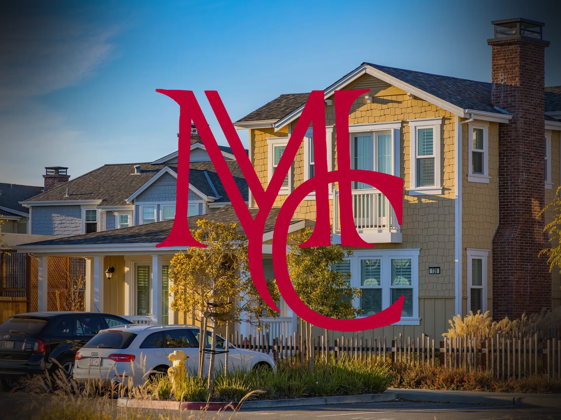 Two-story shingled homes with front porches along a suburban street at golden hour — MCG