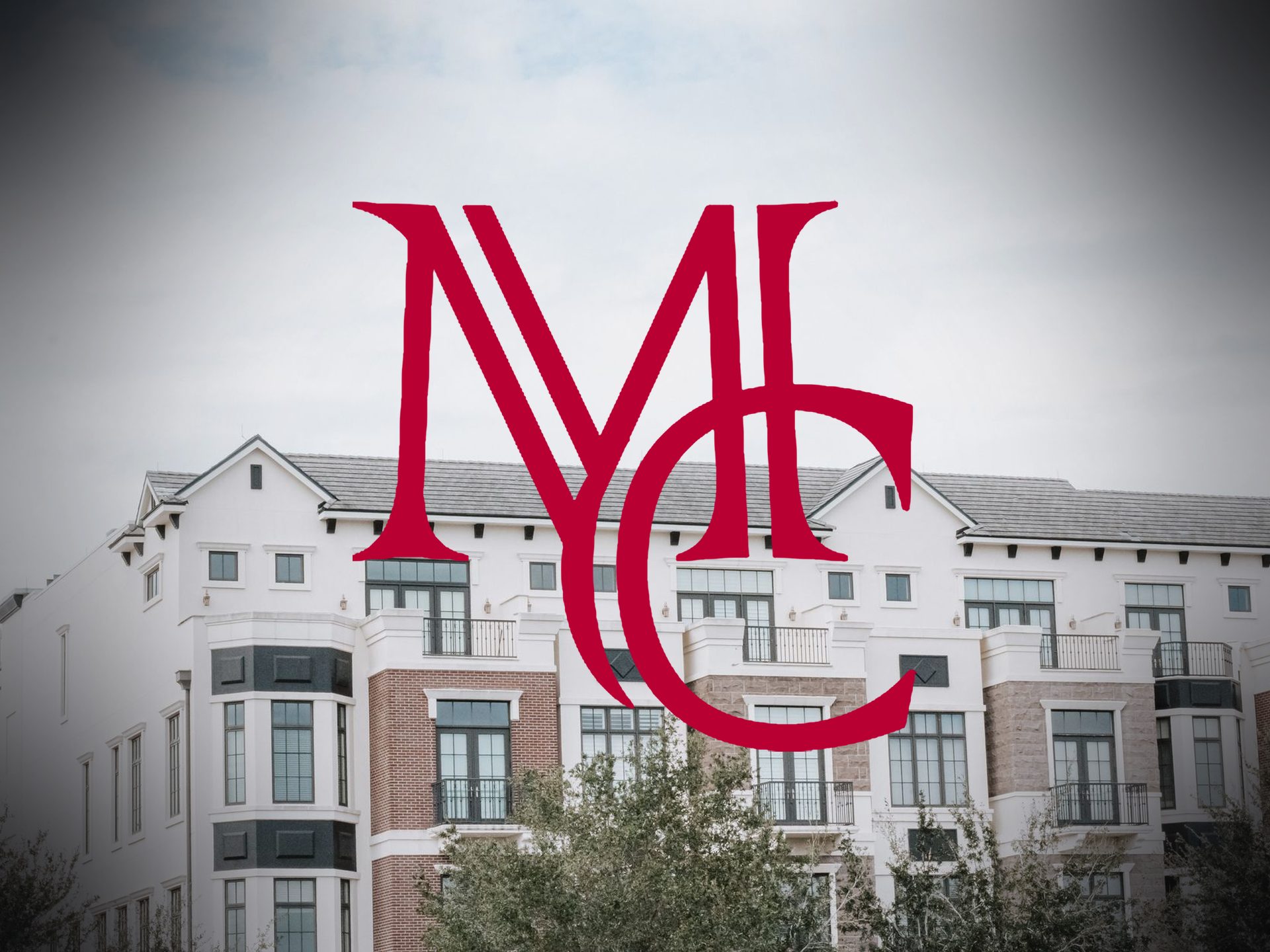 White and brick apartment building with balconies with the crimson Mason Capital Group monogram, illustrating renting before buying a home