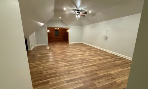 Attic finishing in Naperville IL – open bonus room with vaulted ceiling, recessed lighting, ceiling fan, and new hardwood laminate flooring