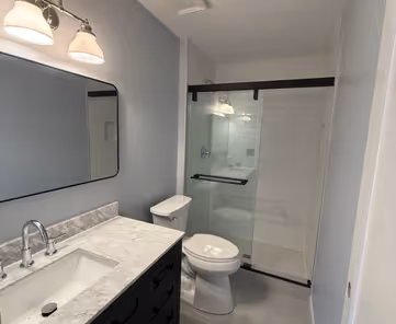 Master bathroom remodel in Naperville IL – full gut renovation with walk-in shower, white subway tile, black sliding glass door, dark vanity with marble countertop and undermount sink