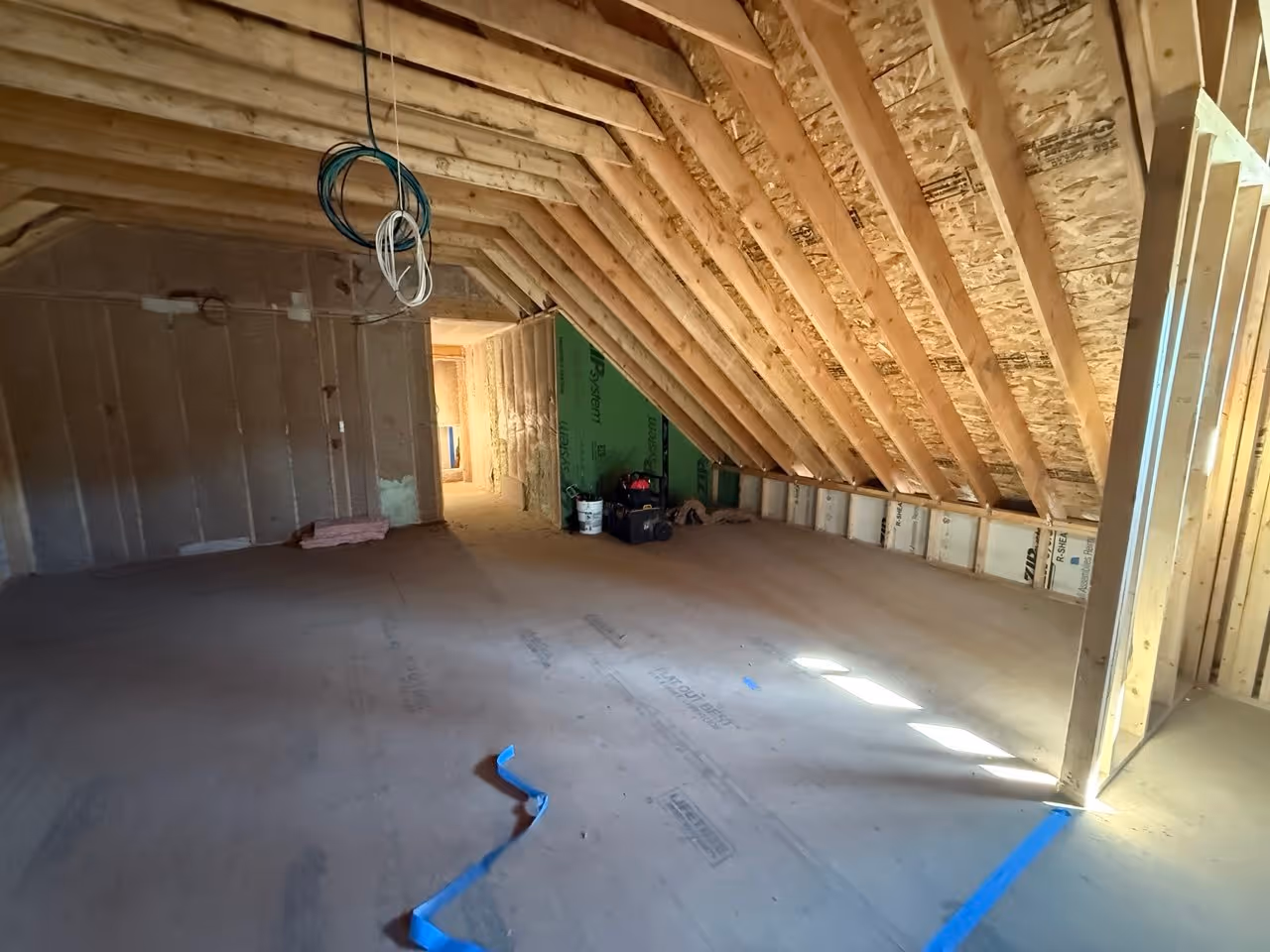 Drywall installation in progress with framed walls, exposed rafters, and unfinished interior space ready for drywall work