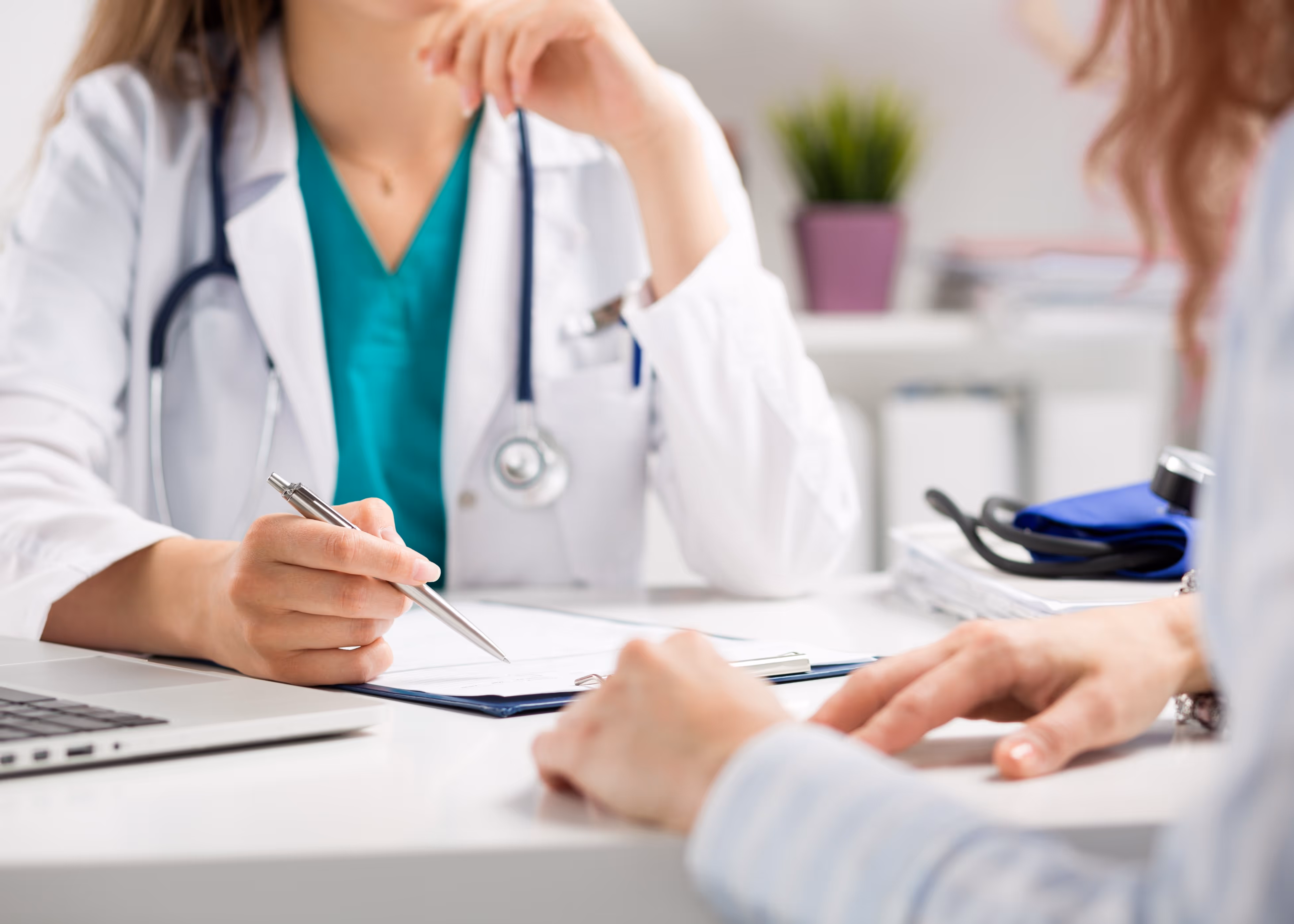 A female doctor sitting at a desk with a laptop.